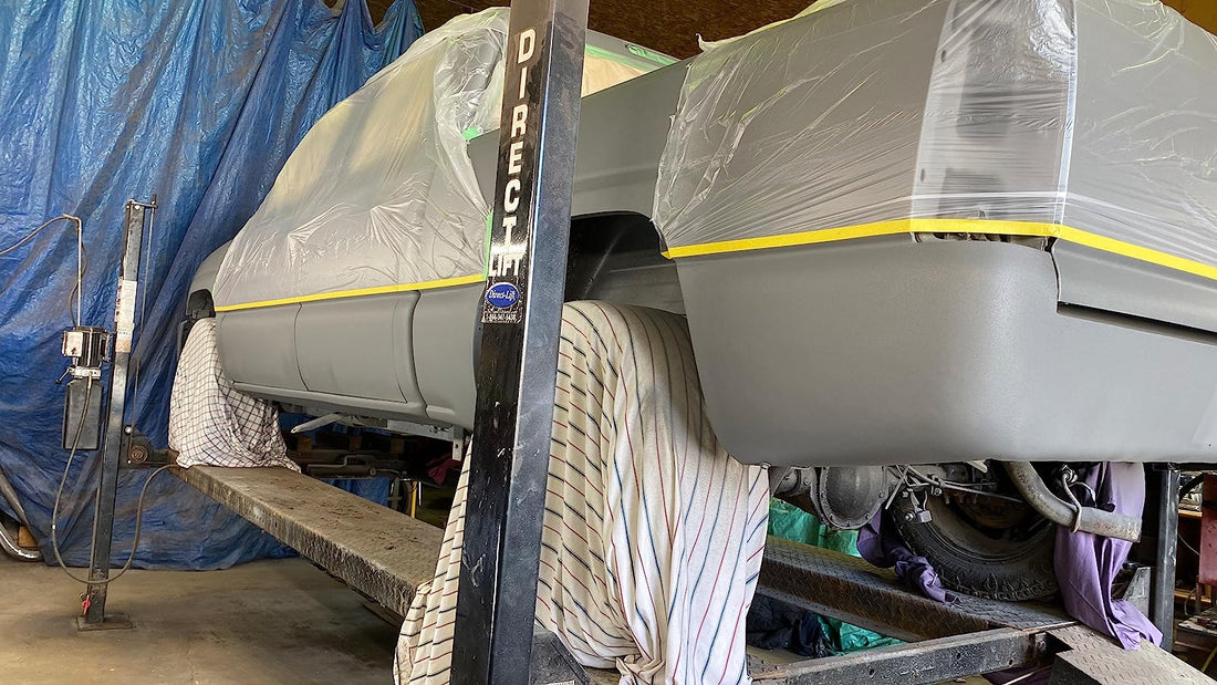 A photo of a pick up truck on a hoist with it's tires cover and a grey cating on the truck. The top half of the truck is covered in pre-taped masking film surface protectant.